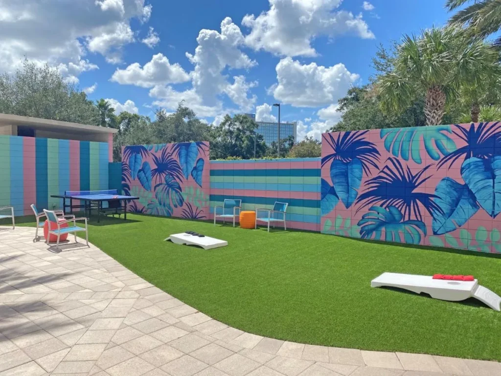 Juegos de césped con cornhole, ping-pong y murales tropicales en el Holiday Inn Orlando Disney Springs