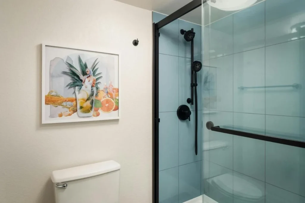 Ducha de cristal con azulejos azules y arte enmarcado en Sheraton Lake Buena Vista Resort