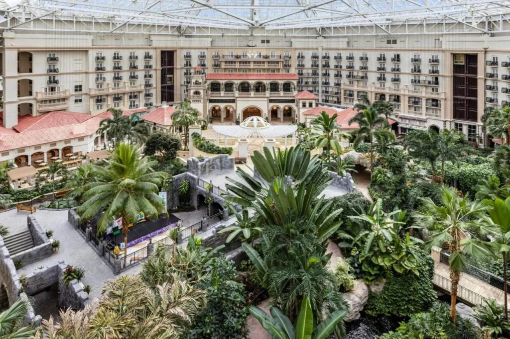 Atrio con techo de vidrio con jardines tropicales, pasarelas y habitaciones con balcones en Gaylord Palms Resort
