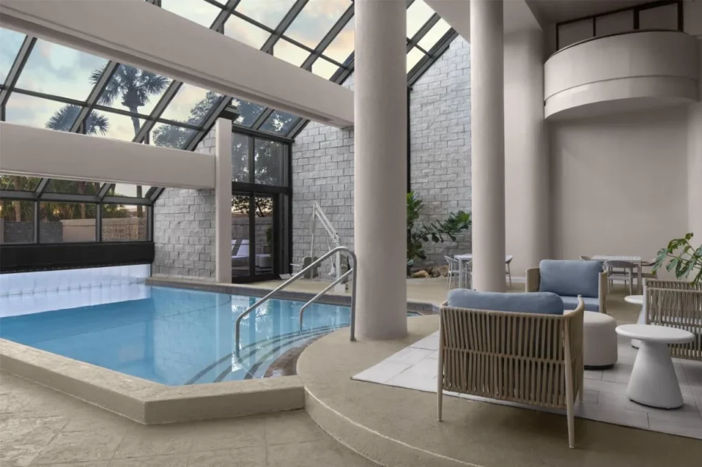 Secci&oacute;n interior con techo de vidrio de la piscina con un elevador de piscina en Embassy Suites ICON Park