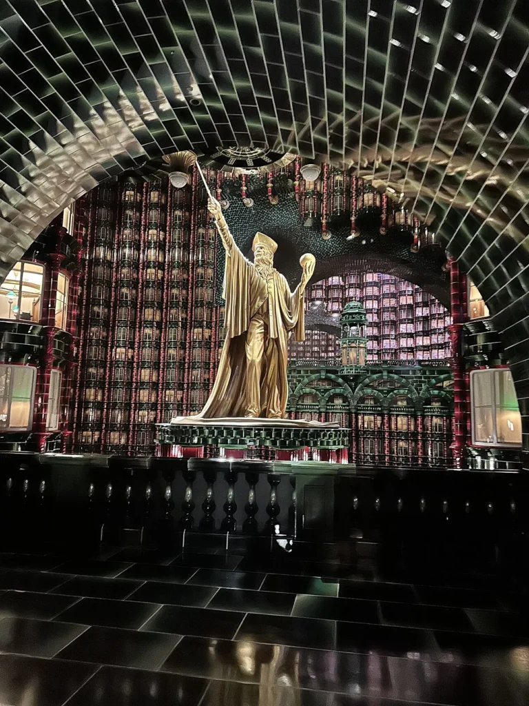 Golden wizard statue under the green tiled arches of the Ministry of Magic, Epic Universe