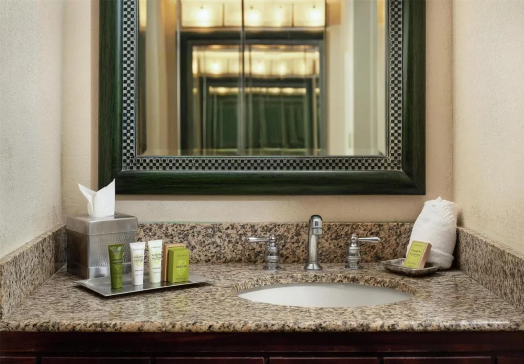 Baño de granito con artículos de tocador y espejo enmarcado en Hilton Orlando Lake Buena Vista