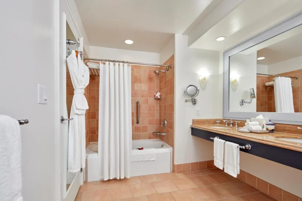 Baño de invitados con bañera, cortina de ducha y bata en Loews Portofino Bay Hotel