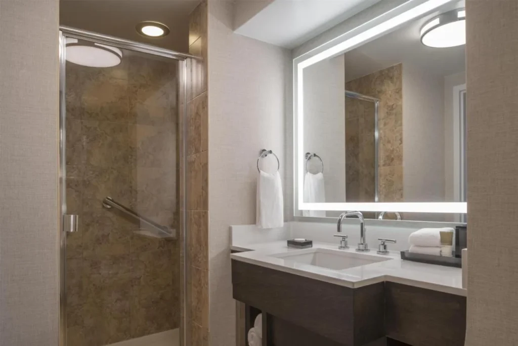 Guest bathroom with walk-in glass shower and lit mirror at Hyatt Regency Orlando International Airport