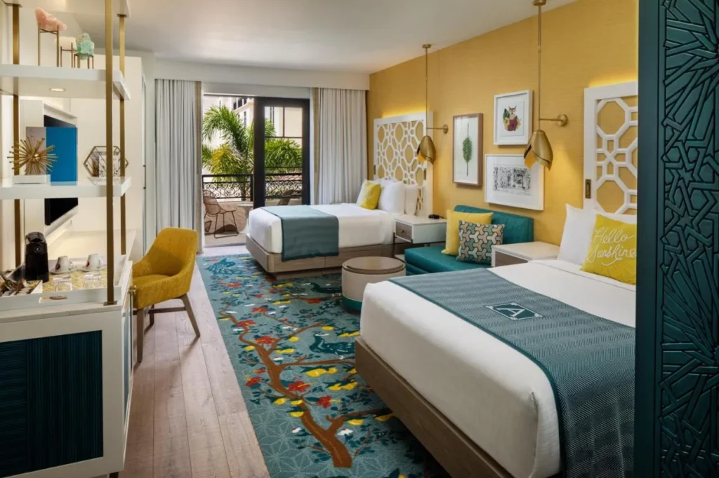 Habitaci&oacute;n en The Alfond Inn con dos camas, paredes amarillas, arte enmarcado y un balc&oacute;n