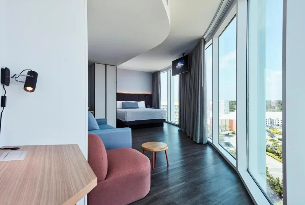 Habitaci&oacute;n en Universal Aventura Hotel con cama, sof&aacute; y ventanas curvas de piso a techo