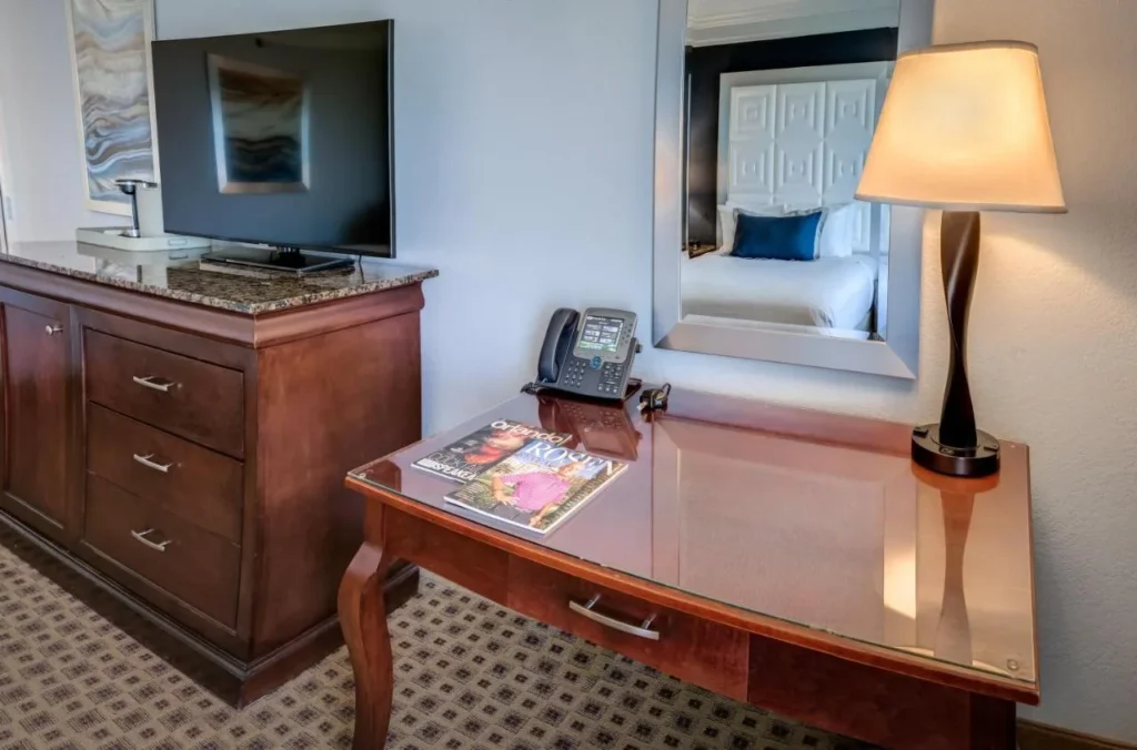 Guest room desk, dresser and flat-screen TV with mirror at Rosen Plaza Hotel