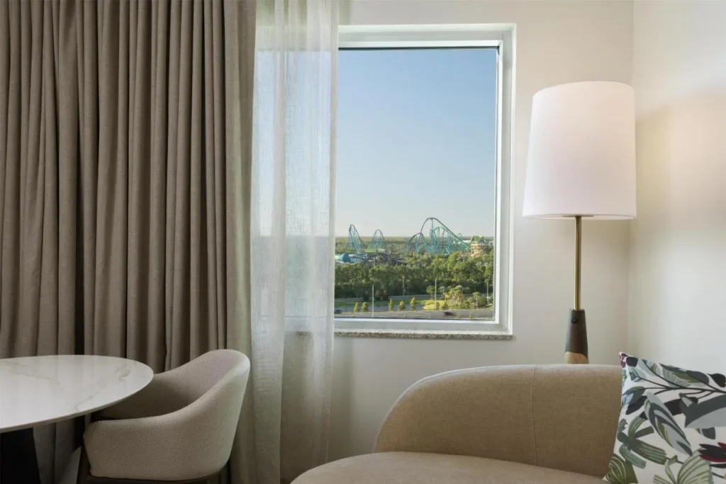 Guest room seating area with a window view of distant roller coasters at Hilton Orlando