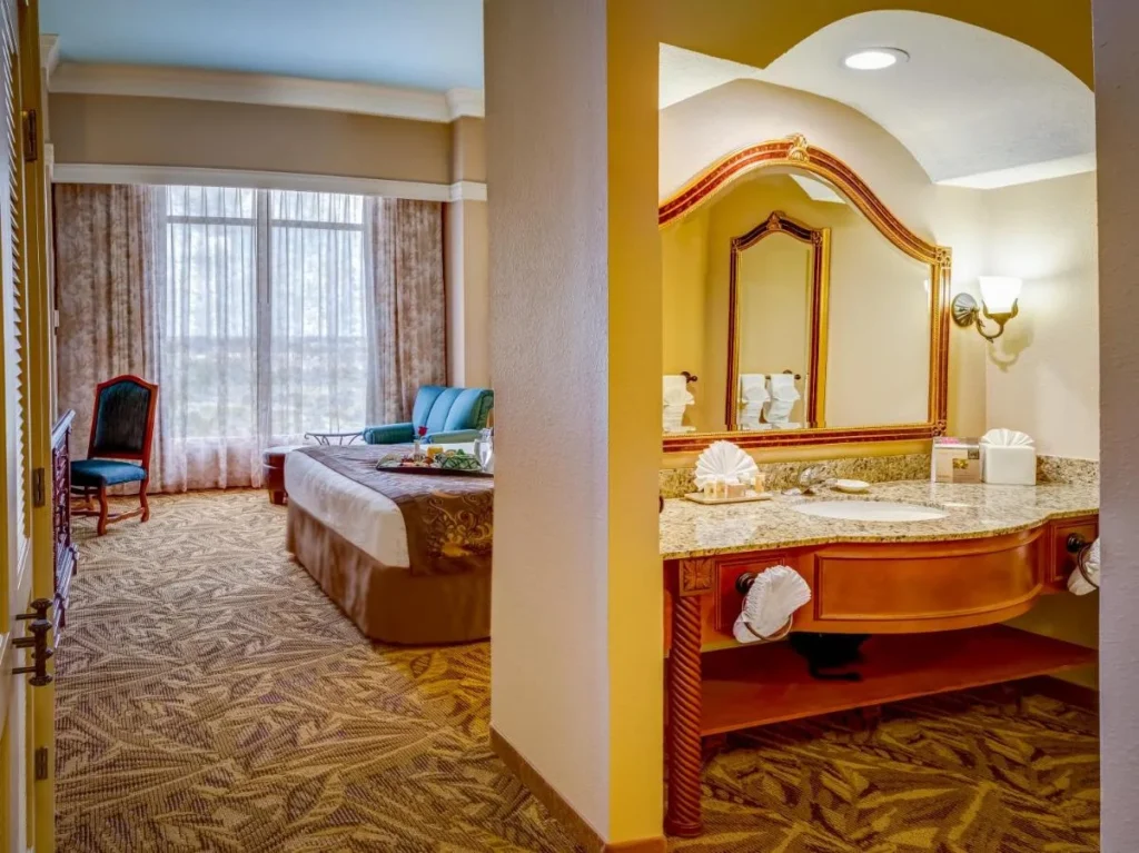 Guest room with a bed, sitting chair and separate vanity area at Rosen Shingle Creek