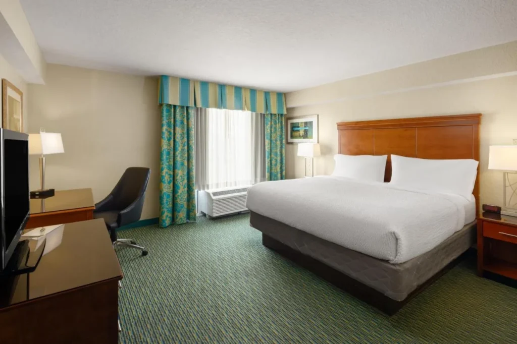 Guest room with a large bed, desk and striped curtains at Holiday Inn Resort Lake Buena Vista