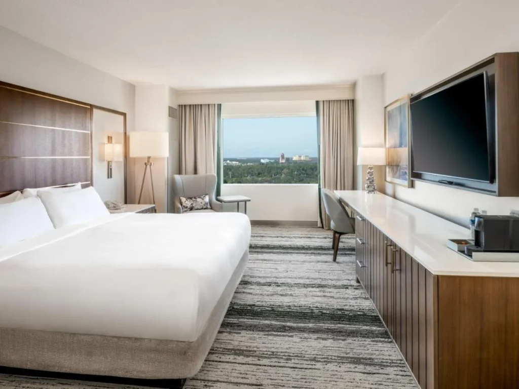 Guest room with a large bed, wall-mounted TV and wide window at Signia by Hilton Orlando