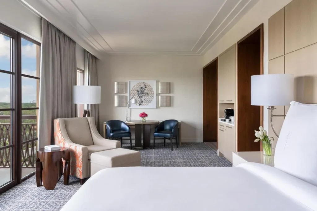 Habitación con cama, sillón, mesa de comedor y puertas de balcón en Four Seasons Resort Orlando
