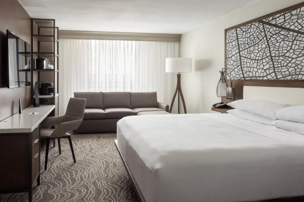 Habitaci&oacute;n con cama king size, sof&aacute;, escritorio y cabecero con patr&oacute;n de hojas en Marriott Orlando Airport Lakeside