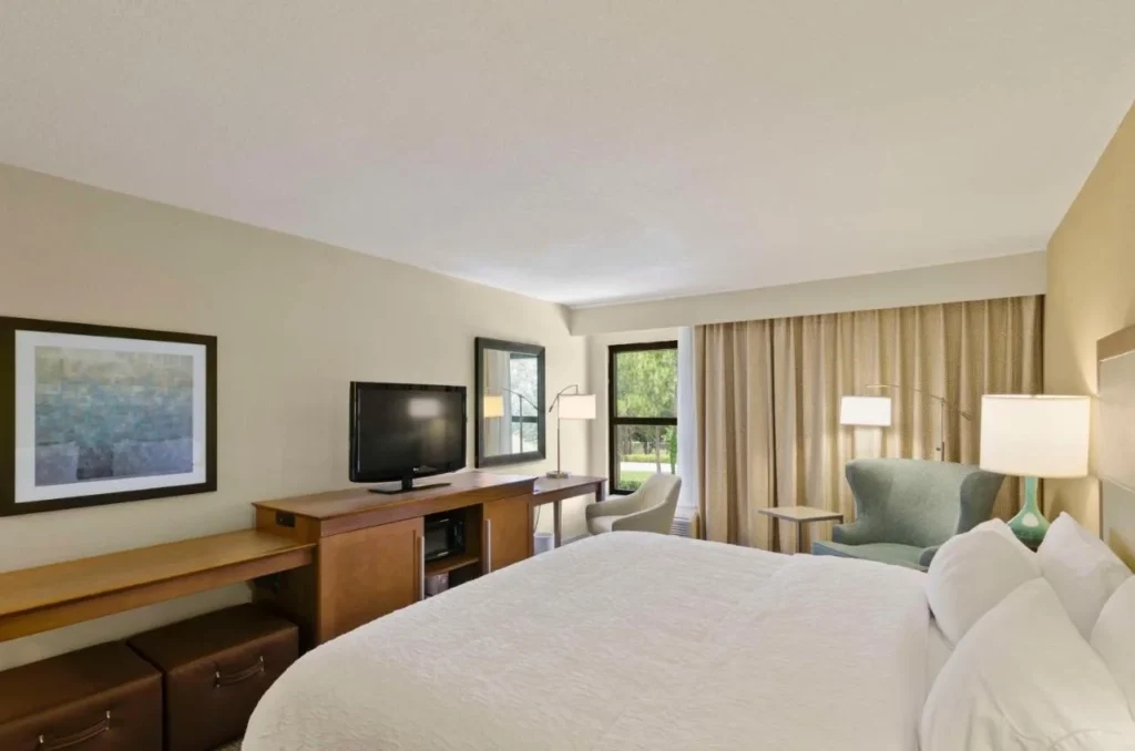 Guest room with large bed, desk, TV and armchairs at Hampton Inn Mount Dora