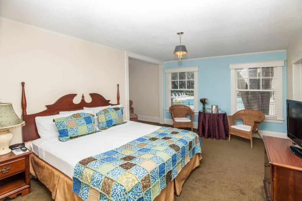 Guest room with patchwork quilt, wicker chairs and windows facing the pool at Lakeside Inn