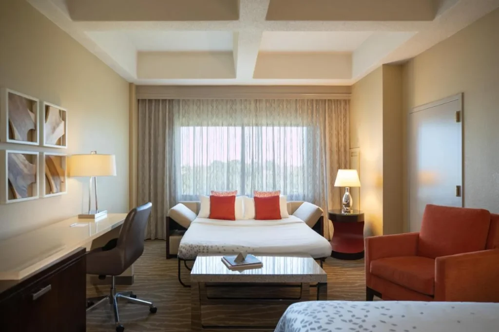 Habitación con sofá cama, escritorio y sillón naranja en Renaissance Orlando at SeaWorld