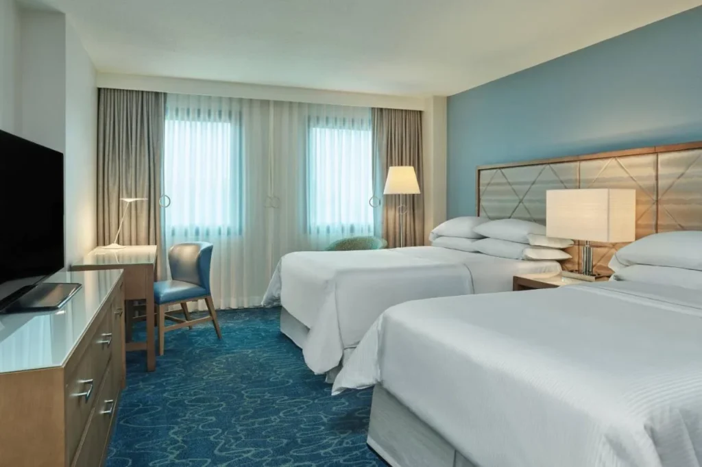 Guest room with two beds, a desk and a long dresser at Walt Disney World Dolphin