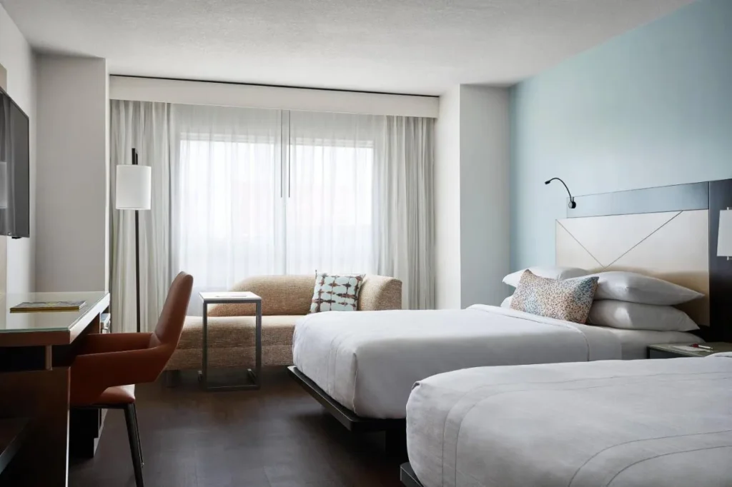 Habitaci&oacute;n con dos camas, una silla de escritorio y un sof&aacute; cama en Marriott Orlando Downtown