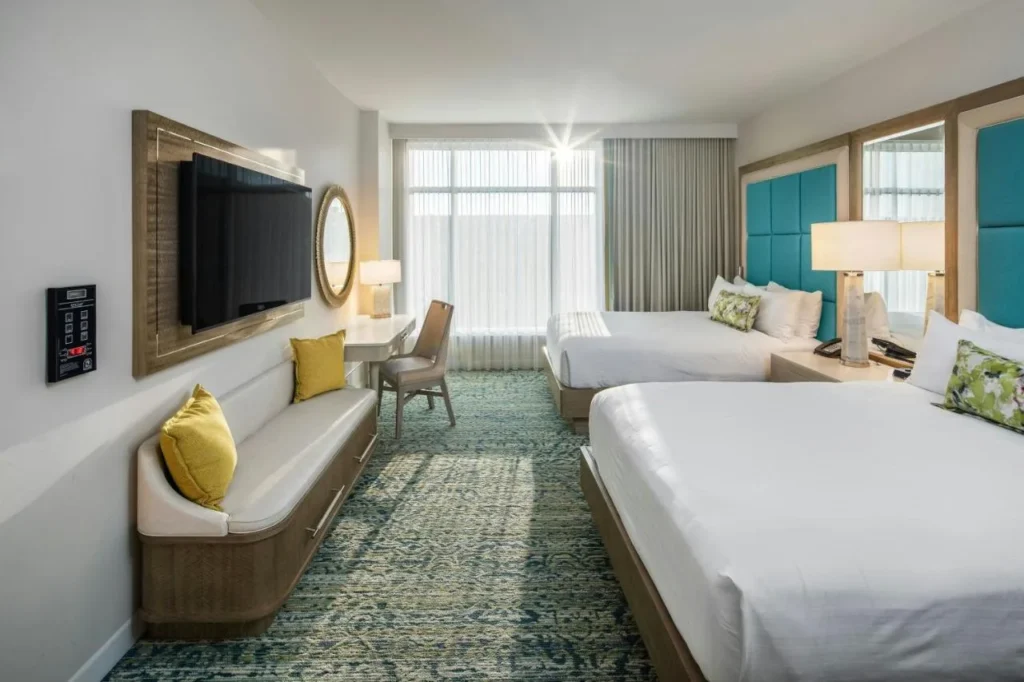 Guest room with two beds, a window bench and teal headboards at Gaylord Palms Resort
