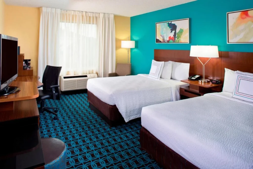 Habitación con dos camas y pared de acento verde azulado en Fairfield Inn & Suites Marriott Village