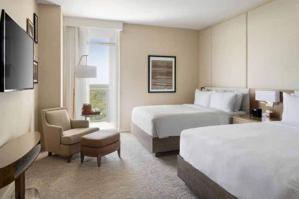 Habitación con dos camas, sillón y otomana en el JW Marriott Orlando Bonnet Creek