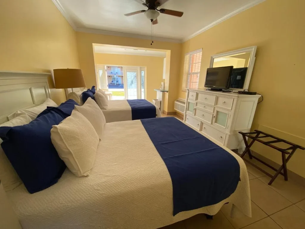 Habitación con dos camas, ventilador de techo y cómoda en Coral Sands Inn Ormond Beach