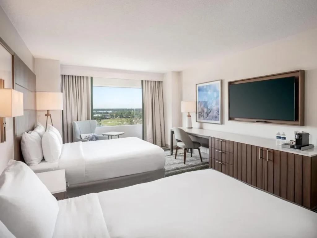 Habitaci&oacute;n con dos camas, escritorio y una ventana sobre el campo de golf en Signia by Hilton Orlando Bonnet Creek