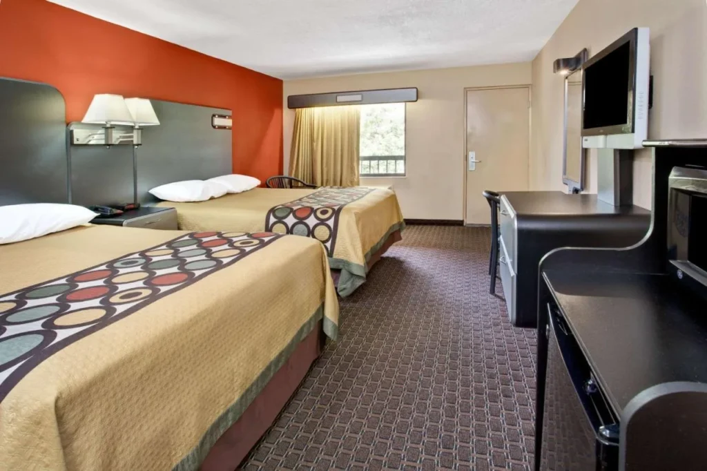 Habitaci&oacute;n con dos camas, escritorio y TV de pared en Super 8 Kissimmee/Maingate
