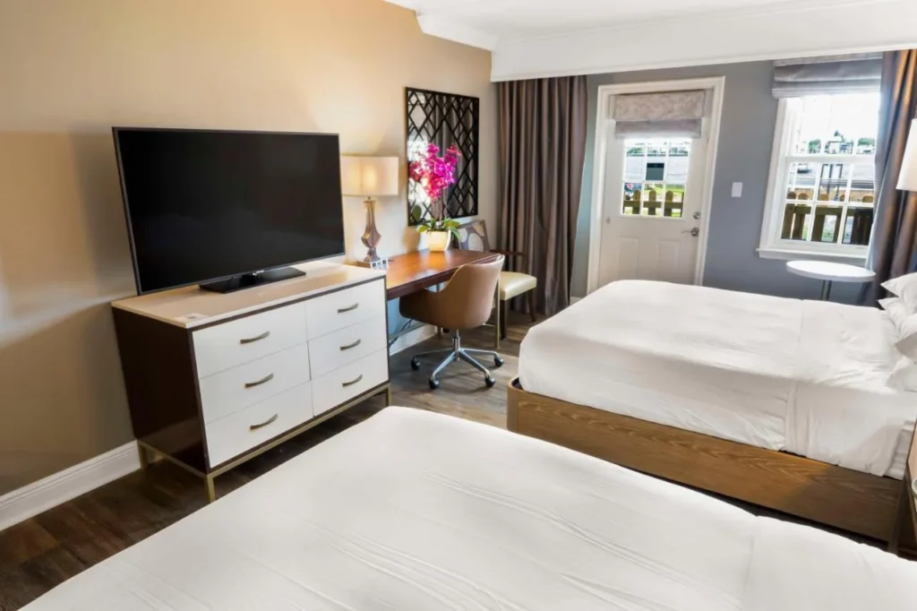 Guest room with two beds, dresser, desk and patio door at Hilton St. Augustine Historic Bayfront
