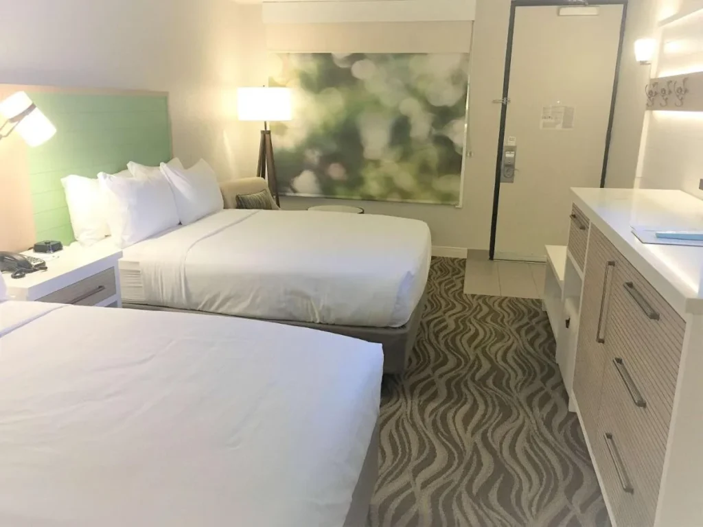 Guest room with two beds, green headboard and long dresser at Wyndham Garden Lake Buena Vista