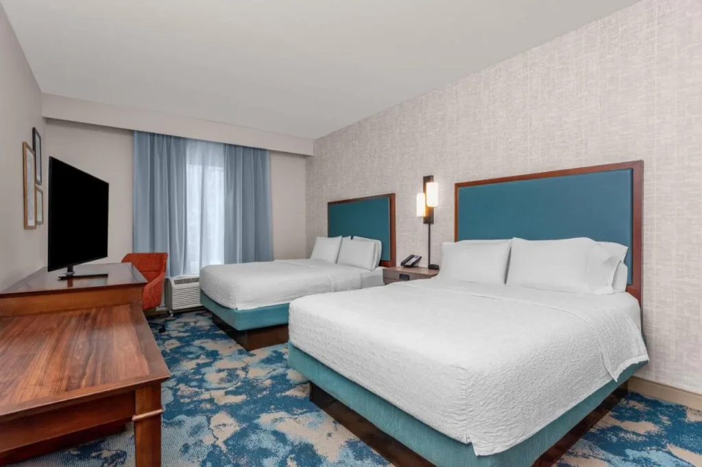 Guest room with two beds, teal headboards and a desk at Hampton Inn and Suites DeLand