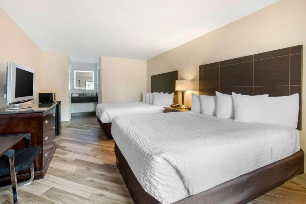 Habitación con dos camas, TV y suelos de madera en Clarion Inn & Suites Kissimmee