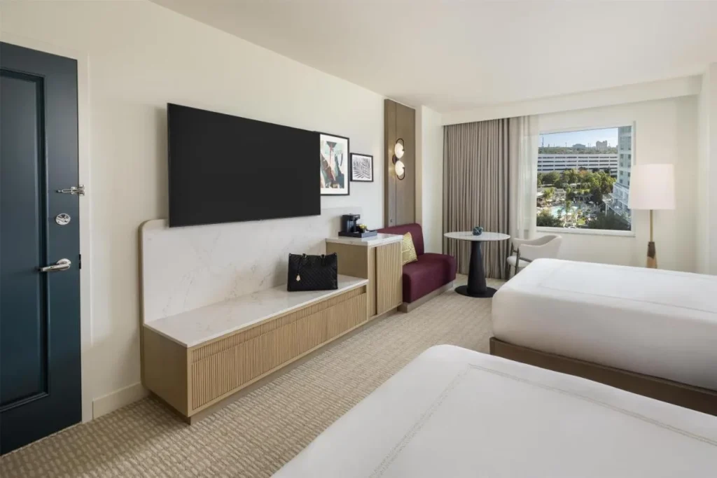 Habitaci&oacute;n con dos camas, TV de pared y zona de estar en la ventana en Hilton Orlando