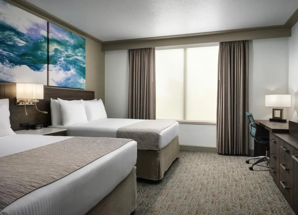 Guest room with two beds, wave artwork and a work desk at Buena Vista Suites Orlando