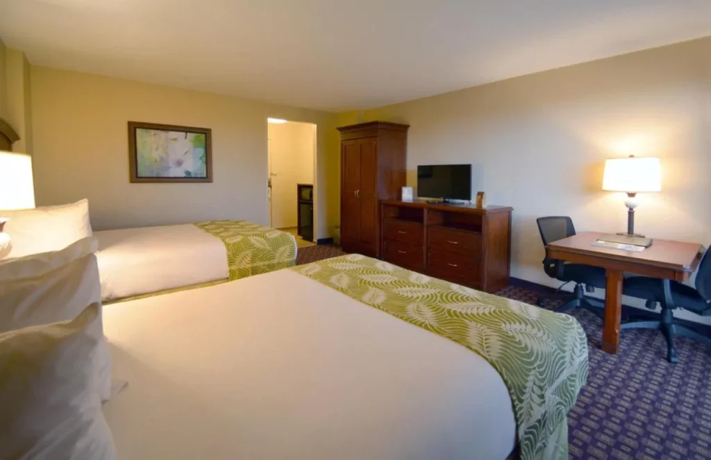 Habitación con dos camas dobles, escritorio y armario en Rosen Inn Closest to Universal