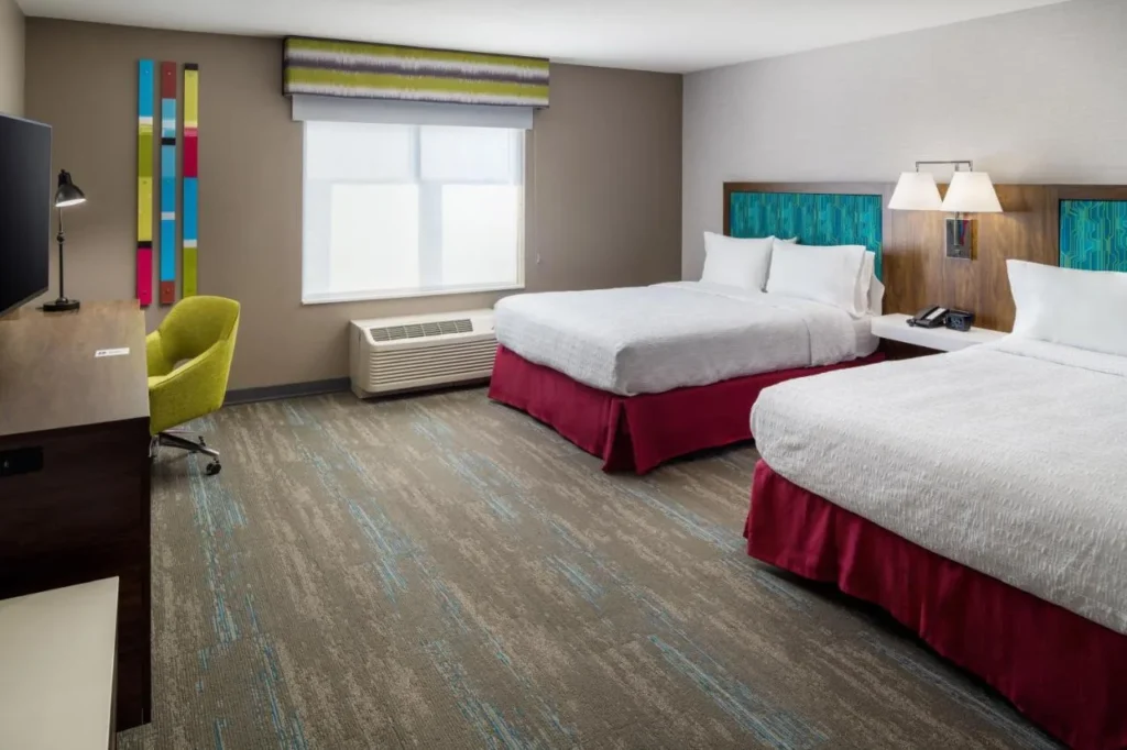 Habitaci&oacute;n con dos camas queen y una silla de escritorio verde en el Hampton Inn Kissimmee North