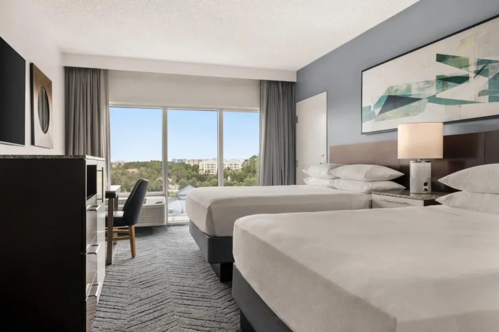 Habitaci&oacute;n con dos camas queen y una gran ventana en Delta Hotels Orlando Celebration