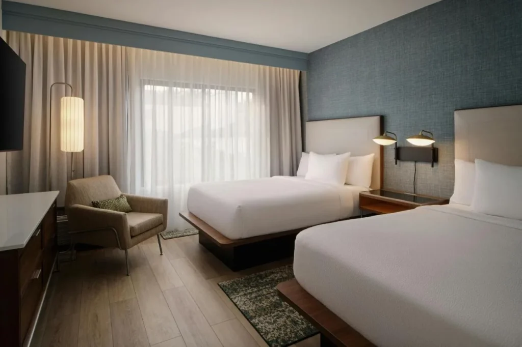 Habitaci&oacute;n con dos camas queen, sill&oacute;n y suelo de madera en el Courtyard Orlando Airport