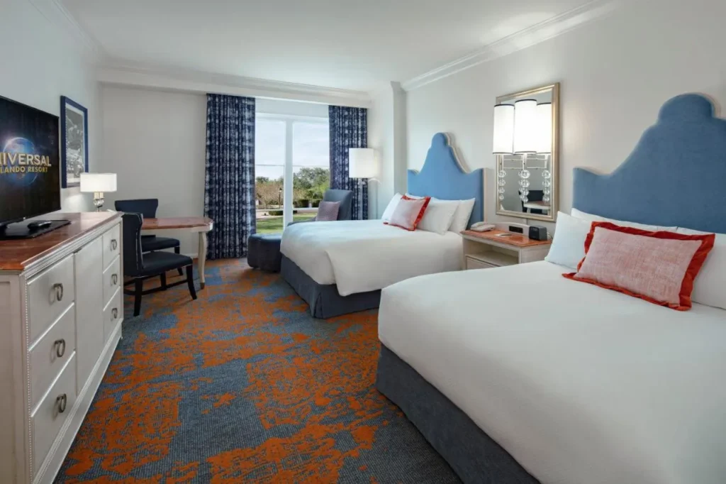 Habitación de dos camas queen con cabeceros azules y una gran ventana en el Loews Portofino Bay Hotel
