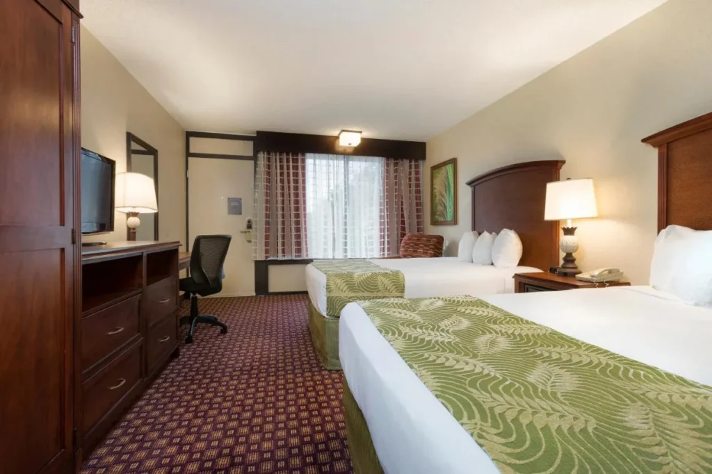 Habitaci&oacute;n con dos camas queen, escritorio y c&oacute;moda de madera en Rosen Inn Internacional