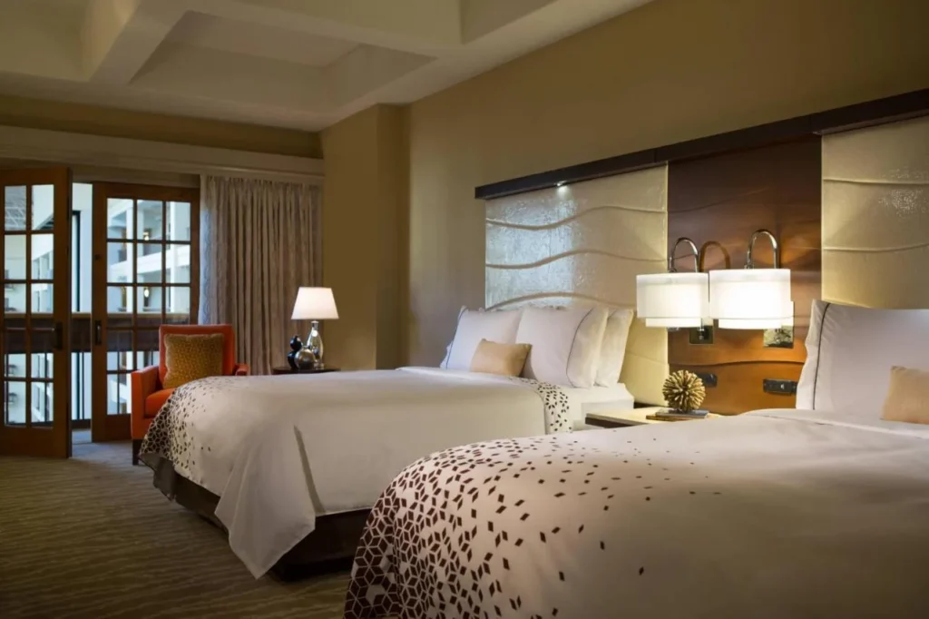 Guest room with two queen beds, orange armchair and atrium doors at Renaissance Orlando at SeaWorld