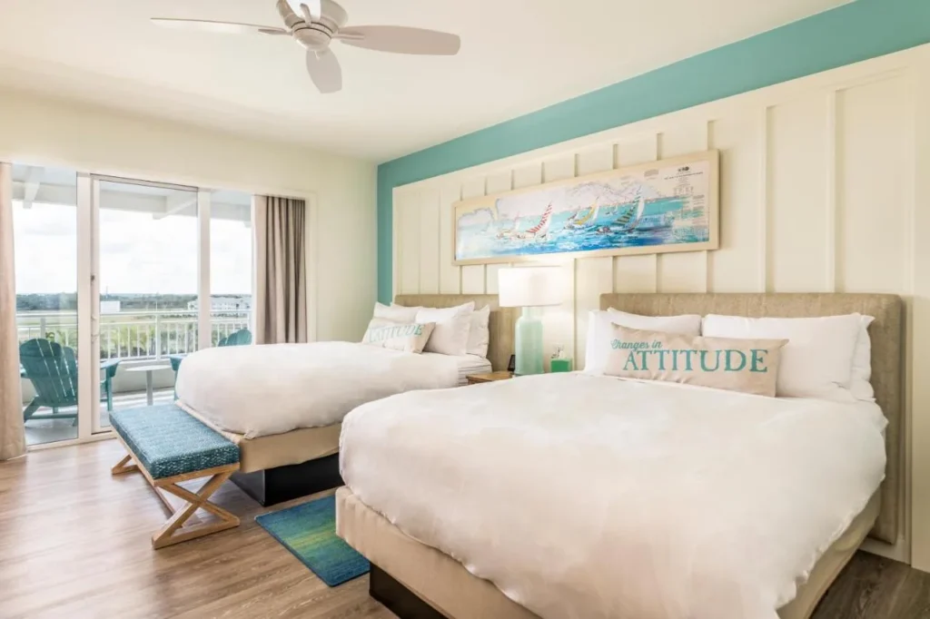 Guest room with two queen beds, sailboat artwork and balcony door at Margaritaville Resort Orlando