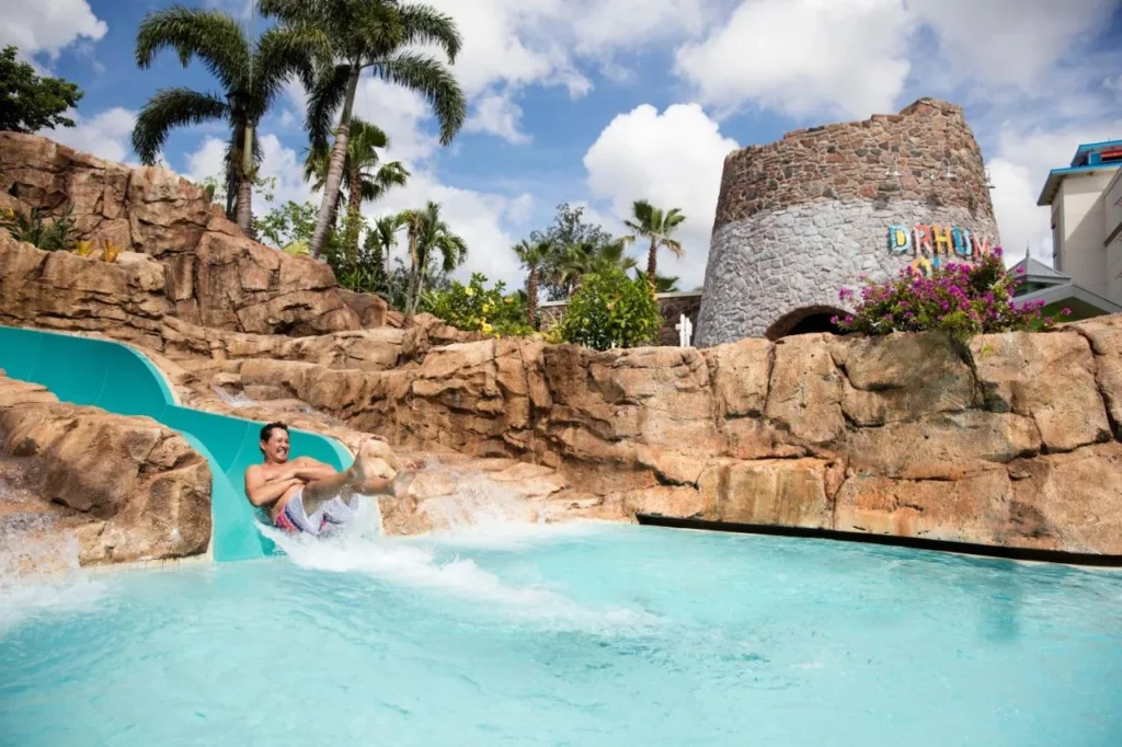 Invitado chapoteando por el tobog&aacute;n de agua enmarcado en la piscina en Loews Sapphire Falls Resort