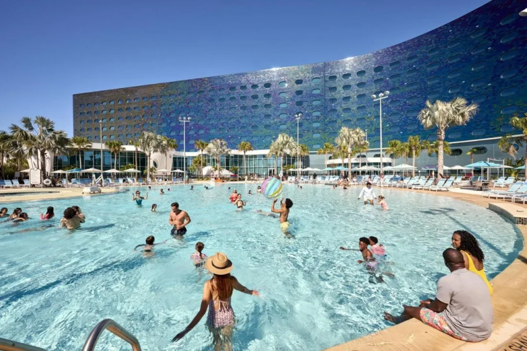 Guests in the pool before the curved blue facade of Universal Terra Luna Resort