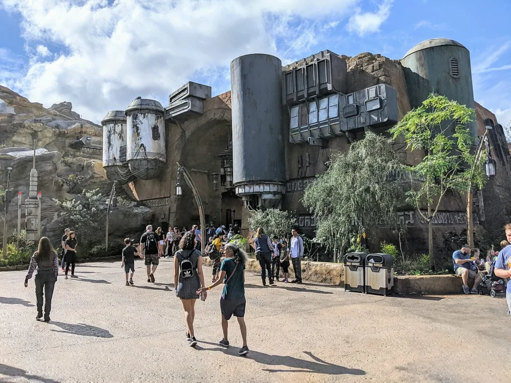 Guests walking past weathered stone buildings of Black Spire Outpost in Galaxy's Edge