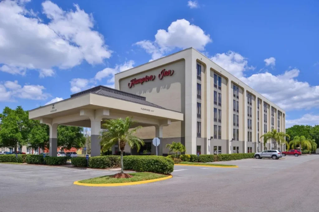 Hampton Inn El exterior más cercano a Universal Orlando con entrada cubierta, palmeras y estacionamiento
