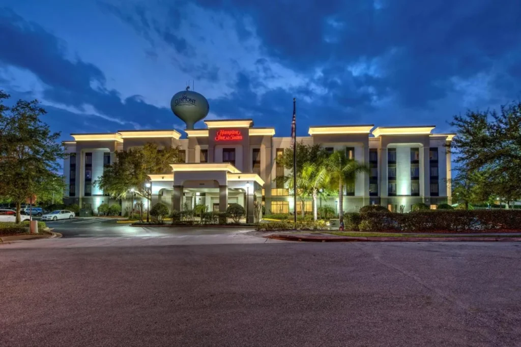 Hampton Inn & Suites Clermont se ilumin&oacute; al atardecer con la torre de agua de Clermont detr&aacute;s