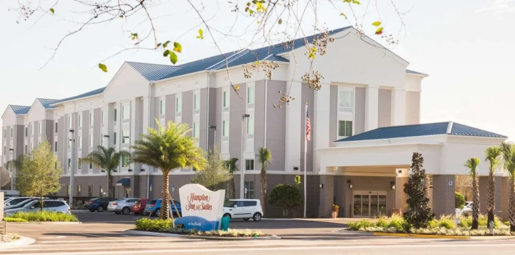 Hampton Inn & Suites Orlando at SeaWorld exterior con su señal de entrada y palmeras