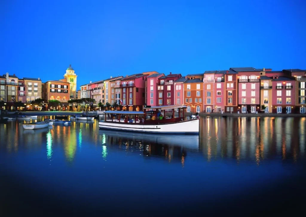 Fachadas iluminadas del puerto por la noche con un barco en el agua en Loews Portofino Bay Hotel