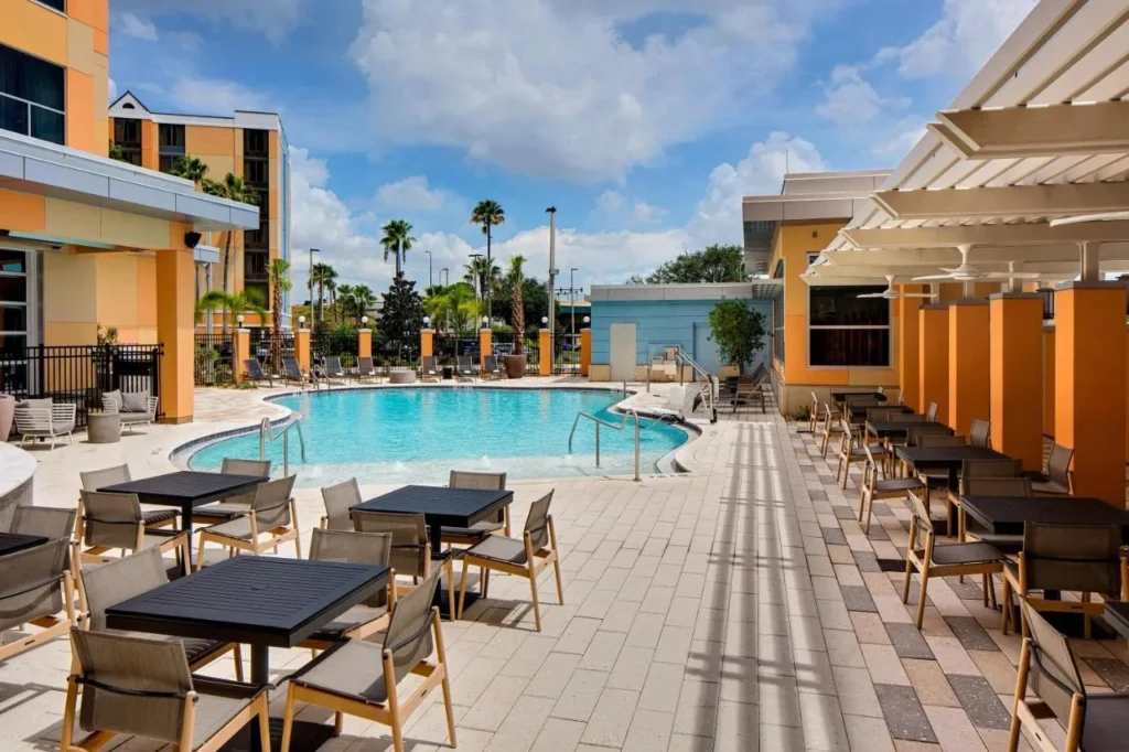 Piscina climatizada al aire libre, mesas de patio y pérgolas en Hyatt House across from Universal Orlando